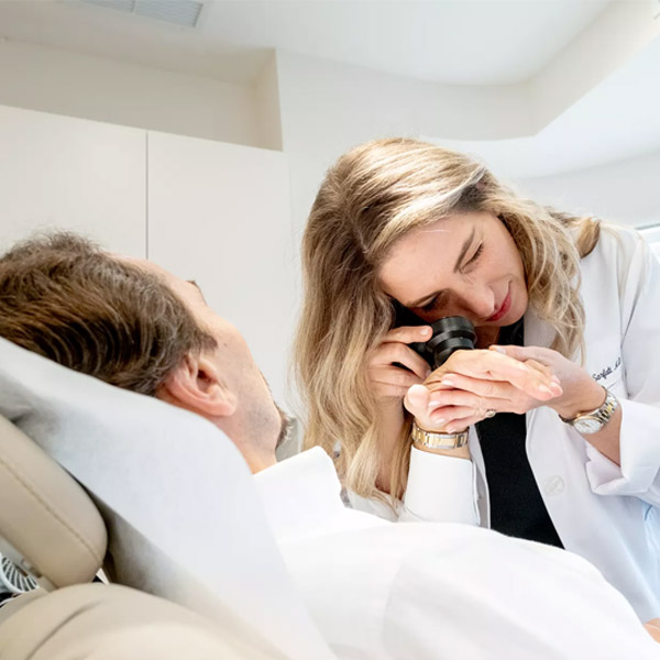 skincare professional looking at clients hand